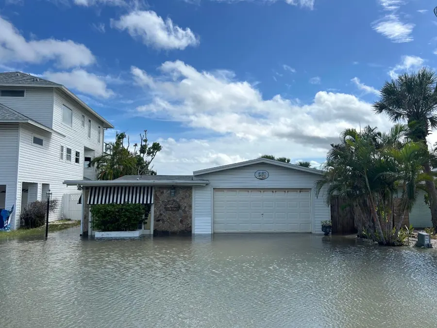 Rising floodwater covering a street and garage in a Gulf coast neighborhood near Punta Gorda